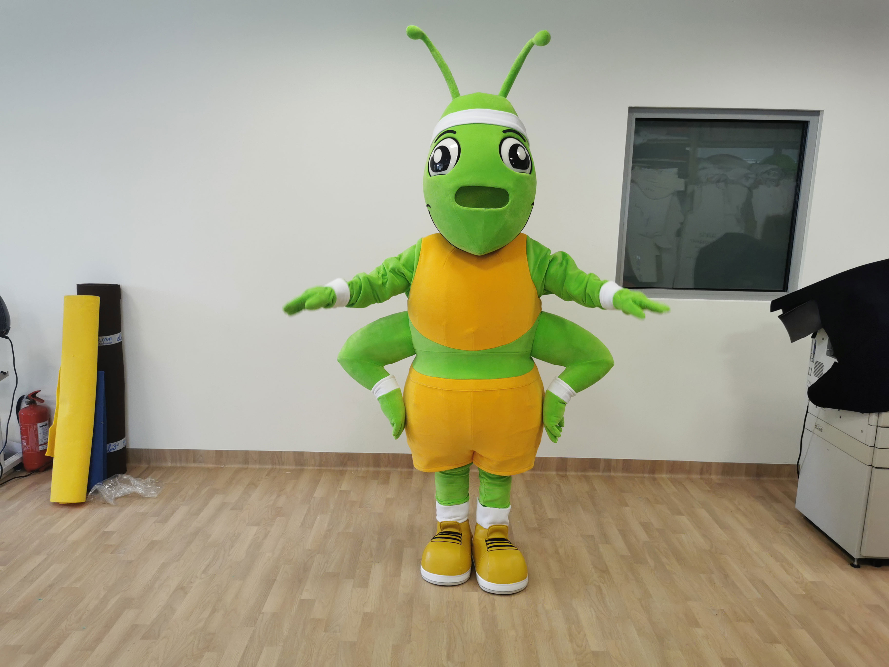 Na fotografii widnieje kostium reklamowy w postaci mrówki pozującej do zdjęcia w siedzibie firmy Elabika
